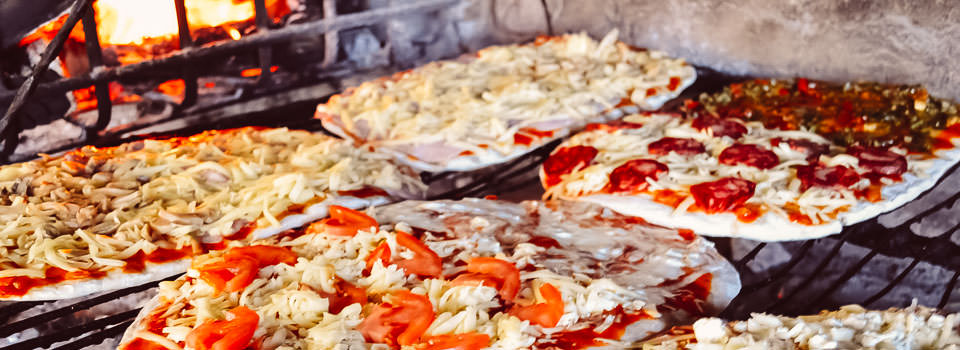 Pizzas a la parrilla cocinándose en un evento.